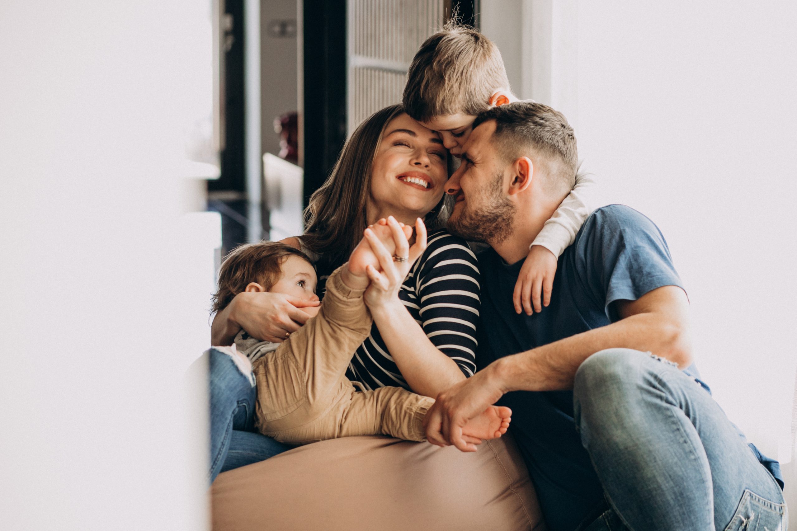 Couple sitting together on a couch with two kids, smiling and relaxed